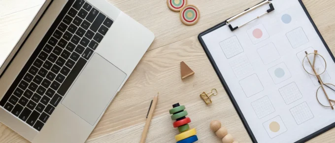 Laptop, forms, and preschool toys on a desk for CDA credential renewal courses.